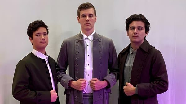 Tres estudiantes del Marist College están en ropa formal frente a un fondo blanco.