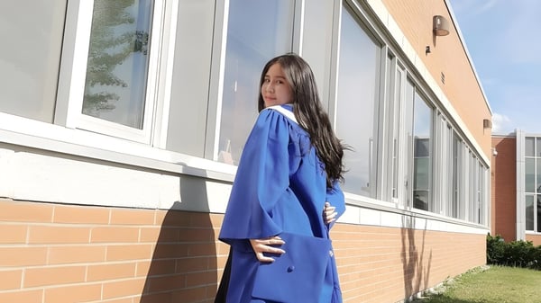 Una estudiante está frente a un edificio de ladrillo en el campus de la Markham District High School.