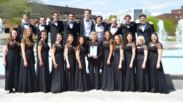 Un grupo de estudiantes de la Marquette High School está en ropa formal frente a una fuente al aire libre.
