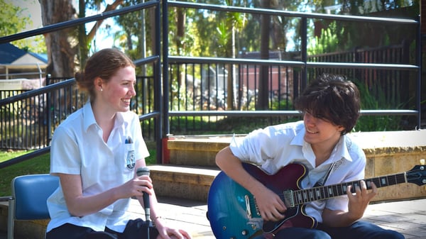 Dos estudiantes de la Marryatville High School están conversando mientras un estudiante toca la guitarra.