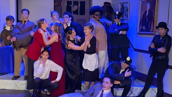 Un grupo de personas en ropa formal y casual en un interior del campus de la Martin Luther High School frente a obras de arte y retratos.