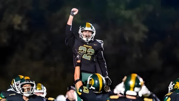 Un jugador de fútbol americano de la Martin Luther High School con el número 22 celebra en el campo con sus compañeros.