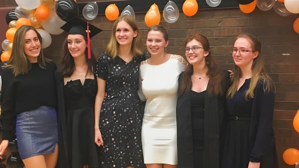 Un grupo de estudiantes posan con ropa formal frente a un fondo festivo en el campus del Martingrove Collegiate Institute.
