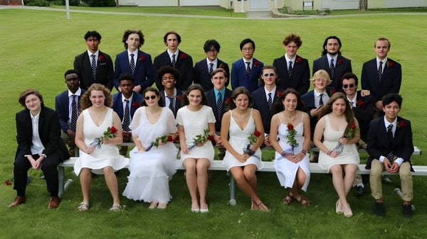 Un grupo de alumnas y alumnos de The Marvelwood School está de pie en un campo frente a un edificio.