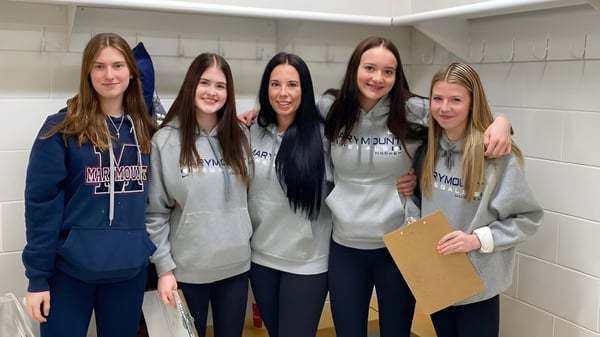 Cinco jóvenes estudiantes están juntas en el pasillo de la Marymount Academy frente a casilleros.