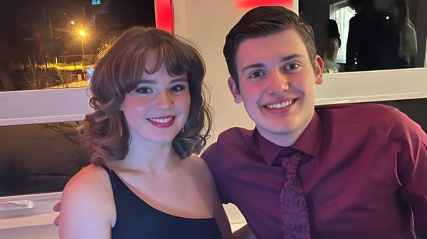 Dos estudiantes sonrientes de la Marymount Academy posan juntos en un restaurante con vista a la ciudad nocturna.