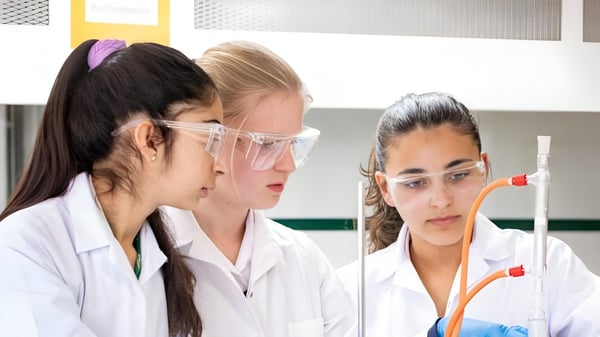 Tres alumnas de la Marymount International School están examinando una muestra en un tubo de ensayo en el laboratorio.