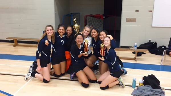 Estudiantes de la Matthew McNair Secondary School celebran su victoria en el gimnasio con trofeos en la mano.