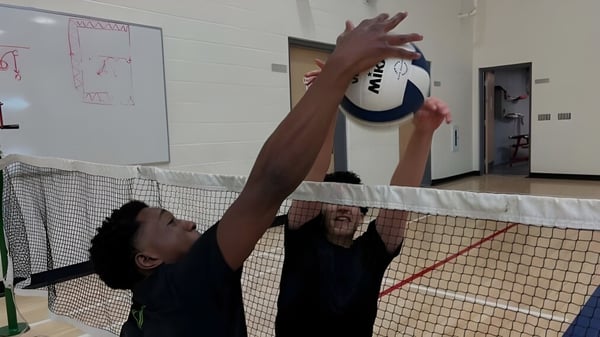 Una persona con camiseta negra juega voleibol en el campo deportivo de la École secondaire publique Maurice Lapointe.
