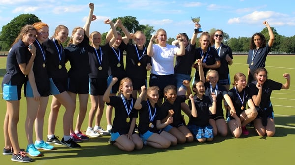 Un grupo de jóvenes deportistas celebra juntas en el campo de deportes de la Mayfield School.