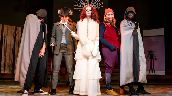 Estudiantes de la Mayfield School están en elaborados trajes juntos en el escenario durante una obra de teatro.