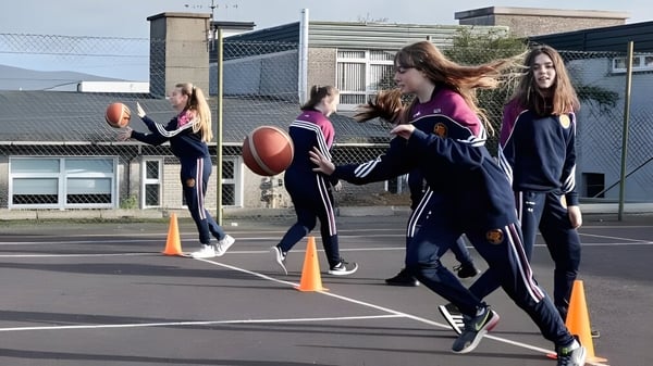 Estudiantes del McEgan College juegan al fútbol en un campo deportivo al aire libre con edificios de fondo.