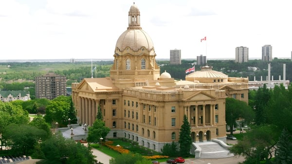 Un imponente edificio gubernamental con cúpula y torre frente a un moderno horizonte en el terreno de la McNally High School.