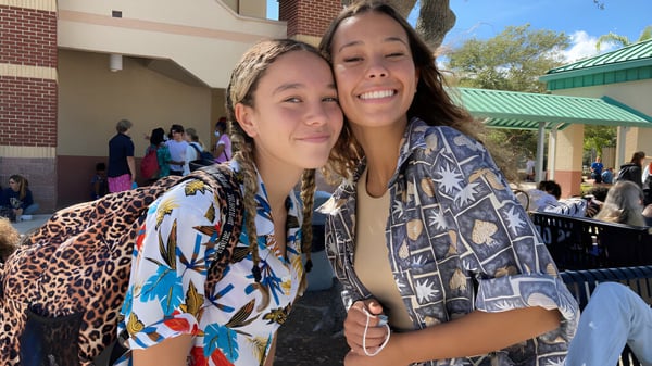 Dos estudiantes sonríen frente a un edificio de ladrillo en el campus de la Melbourne Central Catholic High School.