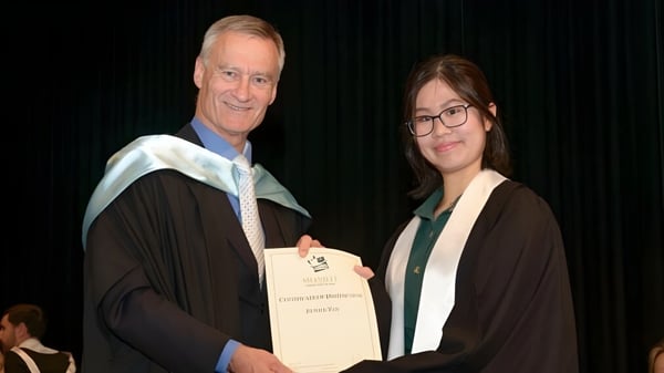 Dos personas llevan togas durante una ceremonia de graduación en la Melville Senior High School en el escenario.