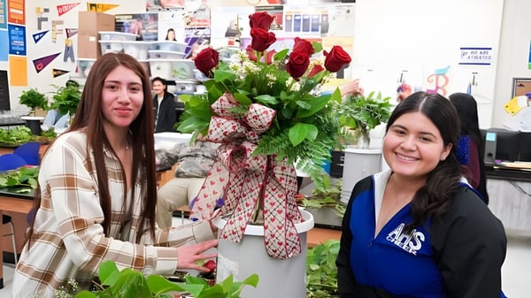 Dos estudiantes del Merced Union High School District están en una floristería entre ramos de flores coloridas y plantas verdes.