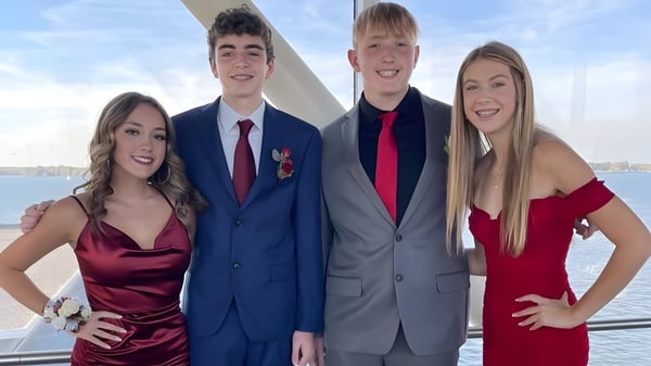 Cuatro estudiantes de la Mercyhurst Prep School posan juntos en un bote con agua y cielo de fondo.