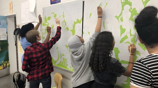 Estudiantes de la Merivale High School trabajan juntos en un colorido mural con elementos artísticos.