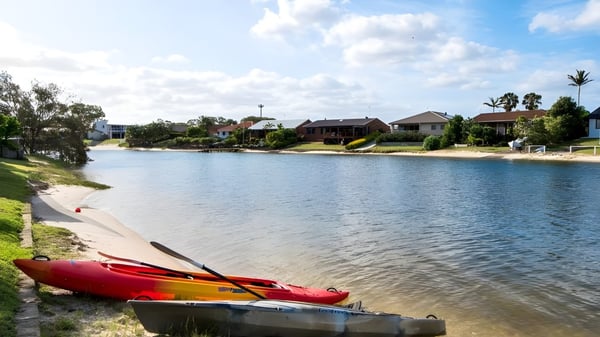 Un kayak rojo está en un lago tranquilo con un entorno verde cerca de la Merrimac State High School.