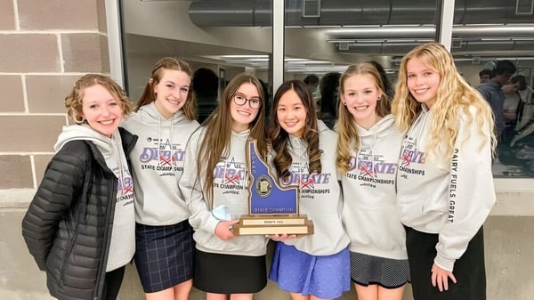 Un grupo de estudiantes en el Mesa Unified School District sostiene juntos un trofeo y posan en un entorno escolar.
