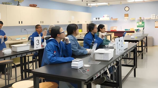 Estudiantes de la Metro International Secondary Academy están sentados en el aula en mesas con materiales de clase.