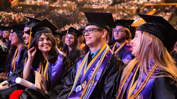 Graduadas y graduados en coloridos trajes de graduación se reúnen en la ceremonia de graduación de la Miami State High School.