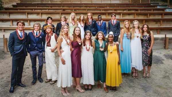 Un grupo de alumnas y alumnos de la Midland School está en escaleras de piedra frente a un edificio de ladrillo.