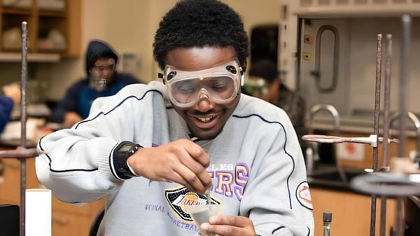 Un estudiante del Milford Public School District está con sudadera gris y gafas de protección en un taller.