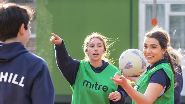 Dos estudiantes de la Mill Hill International en uniformes deportivos conversan en el campo de rugby.