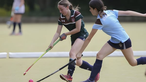 Dos deportistas de la Mill Hill School juegan un partido de hockey en un campo de césped.