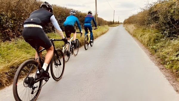 Un grupo de estudiantes de la Milton Abbey School monta en bicicleta por un camino pavimentado a través de la naturaleza.