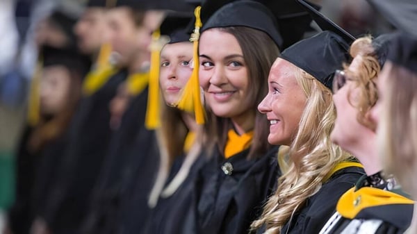 Los graduados de la Milton Abbey School celebran juntos su graduación en togas y birretes negros.