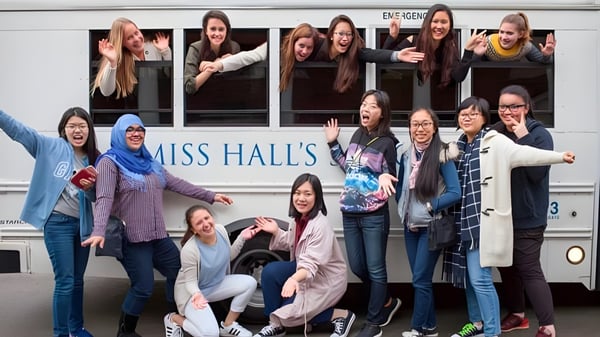 Un grupo de alumnas posan frente a un autobús con la inscripción Miss Hall's School.