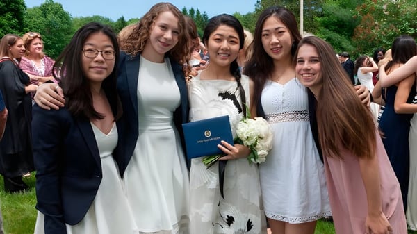 Un grupo de mujeres jóvenes está juntas en el área verde del campus de la Miss Hall’s School.
