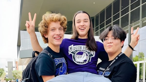Tres estudiantes muestran signos de paz con las manos en el campus de la Mission Heights Preparatory High School.