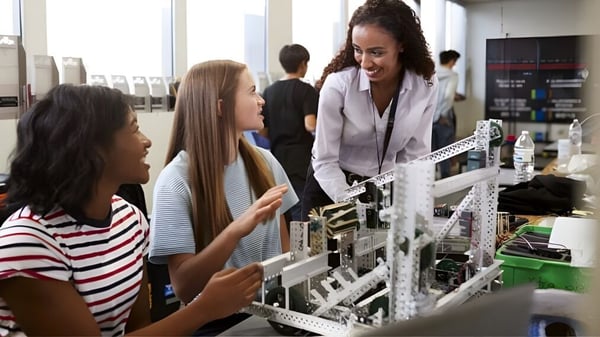 Estudiantes de la Mitchell District High School examinan juntos un proyecto de robótica bajo la supervisión en clase.