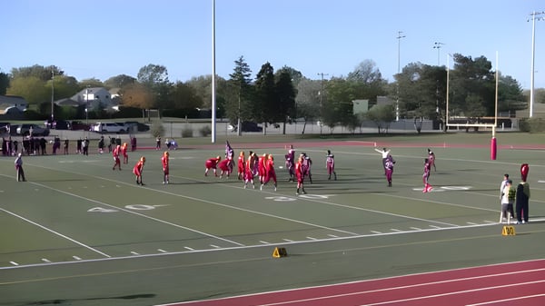 Dos equipos en camisetas rojas y blancas juegan en el campo de deportes de la M.M. Robinson High School.