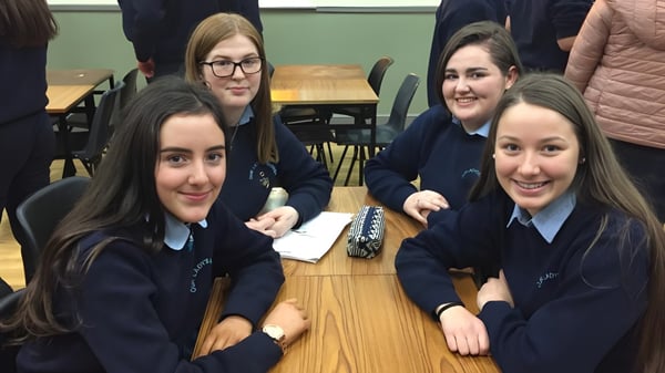 Un grupo de alumnas se sienta juntas en una mesa en el aula del Moate Community College y conversan.