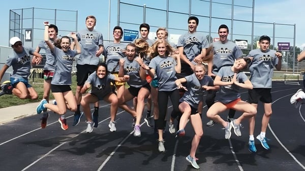 Un grupo de estudiantes en ropa deportiva posan juntos en un campo deportivo en el campus de la Monarch High School.