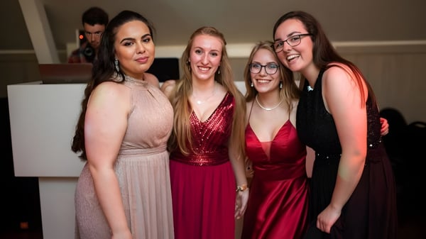 Cuatro alumnas de la Monmouth School for Girls posan en ropa festiva juntas en una celebración.