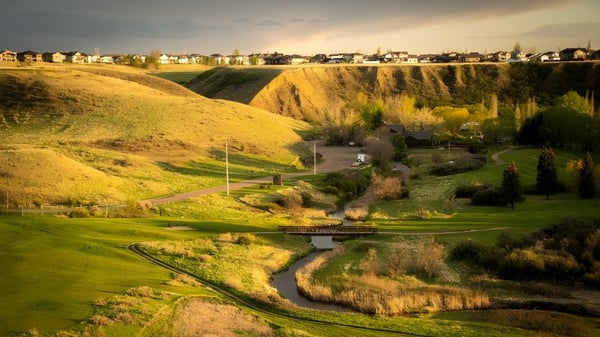 Un paisaje verde con un camino sinuoso y un pueblo al fondo cerca de la Monsignor McCoy High School.