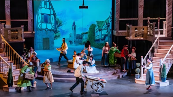 Un grupo de estudiantes de la Monte Vista Christian School en una actuación teatral con trajes históricos y un fondo de ciudad europea.