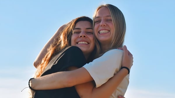 Dos estudiantes se abrazan bajo un cielo despejado en el terreno de la Monterey Bay Academy.