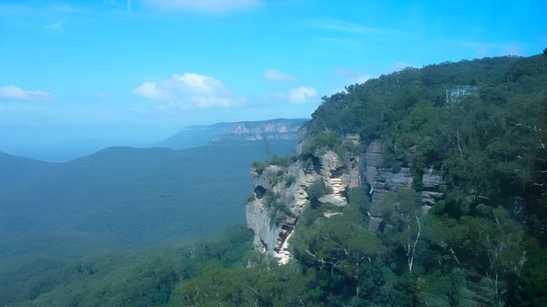 Vista de acantilados rocosos sobre un valle boscoso bajo un cielo azul sin relación directa con la Mount Barker High School.