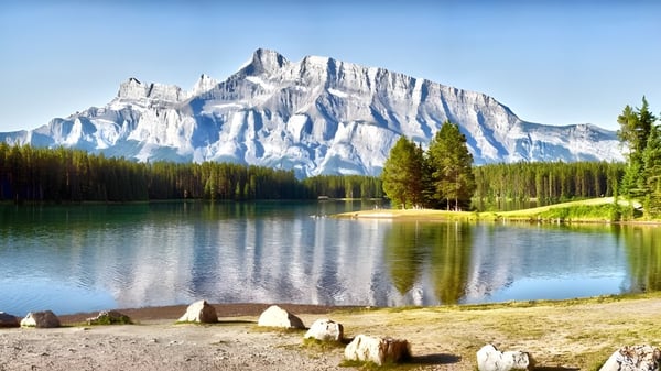 Un tranquilo lago de montaña con cumbres nevadas y una orilla boscosa cerca de la Mount Boucherie Secondary School.