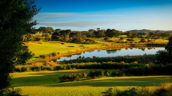 Un campo de golf bien cuidado con un lago y colinas en el terreno de la Mount Compass Area School.