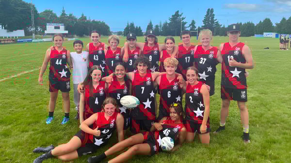 Un grupo de jugadoras de fútbol con camisetas rojas y negras está en un campo de juego en el campus del Mount Hutt College.