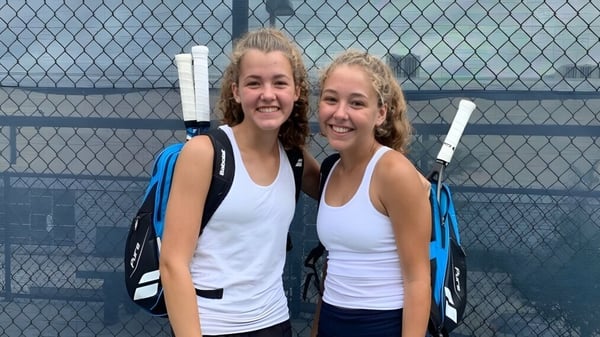 Dos estudiantes están juntas frente a una cerca de alambre en el campus de la Mount Lebanon High School.