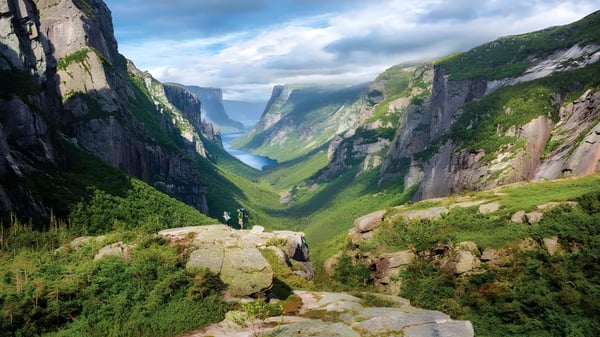 Paisaje montañoso con acantilados empinados y un valle verde bajo un cielo nublado cerca de la Mount Pearl Senior High School.