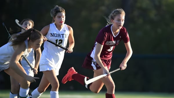 Tres estudiantes de la Mount Sackville Secondary School juegan de noche en el campo deportivo en un campo cubierto de hierba.